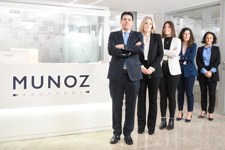 Los cinco profesionales de Muñoz Abogados en la recepción de su despacho, junto al rótulo del bufete