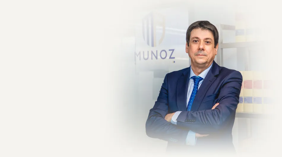 Antonio Muñoz junto a la biblioteca jurídica del despacho, con el rótulo del bufete al fondo